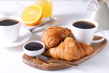 Tasty breakfast. Cup of coffee, jam and croissants on white wooden table