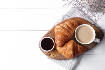 Tasty breakfast. Cup of coffee, jam and croissants on white wooden table, top view. Space for text