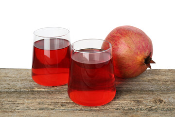 Refreshing pomegranate juice in glasses and fruit on wooden table against white background