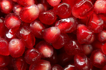 Ripe juicy pomegranate grains with water drops as background, top view