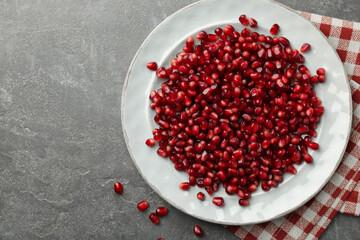 Tasty ripe pomegranate grains on grey table, top view. Space for text