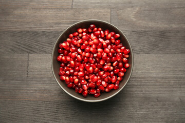 Tasty ripe pomegranate grains on dark wooden table, top view