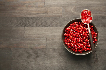 Tasty ripe pomegranate grains on dark wooden table, top view. Space for text
