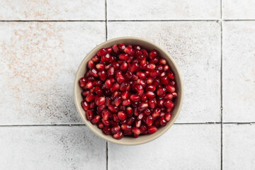 Tasty ripe pomegranate grains on tiled table, top view