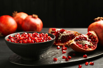 Tasty ripe pomegranates and grains on dark wooden table