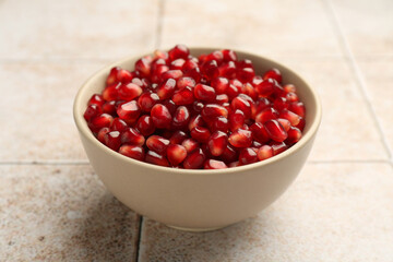 Tasty ripe pomegranate grains on tiled table, closeup