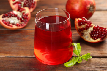 Tasty pomegranate juice in glass and fresh fruits on wooden table, closeup
