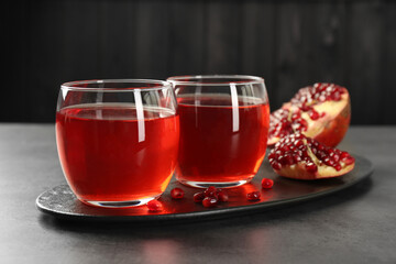 Tasty pomegranate juice in glasses and fresh fruit on grey table