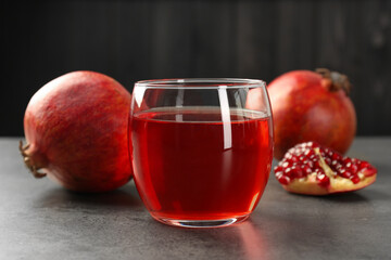 Tasty pomegranate juice in glass and fresh fruit on grey table