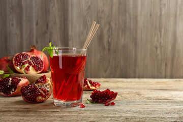 Tasty pomegranate juice in glass and fresh fruits on wooden table. Space for text
