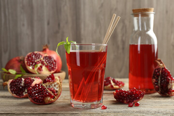 Tasty pomegranate juice in glass and fresh fruits on wooden table