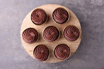 Delicious chocolate cupcakes on grey textured table, top view