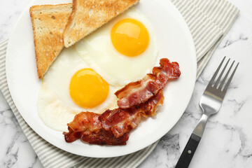 Delicious breakfast with sunny side up eggs served on white marble table, flat lay