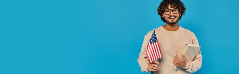 A man in casual attire holds a clipboard with an American flag in the background, showing...