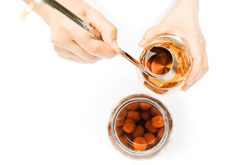 Umeshu, Japanese plum wine, in jar, woman hand use stainless steel ladle dip golden umeshu into...