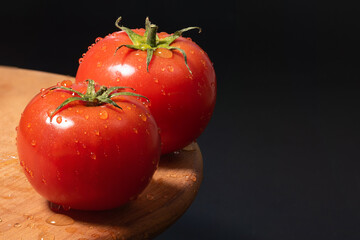Fresh tomatoes with water drops on a black background close-up. - 783112202