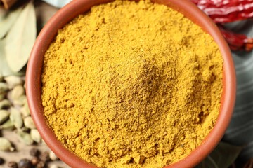 Curry powder in bowl and other spices on table, top view