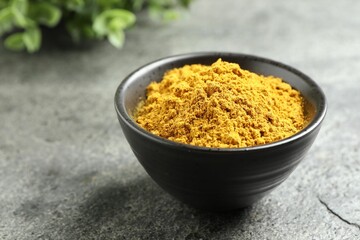 Dry curry powder in bowl on dark textured table, closeup