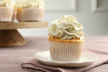 Tuinposter Tasty cupcake with vanilla cream on pink wooden table, closeup © New Africa