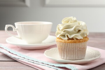 Tasty cupcake with vanilla cream on pink wooden table, closeup