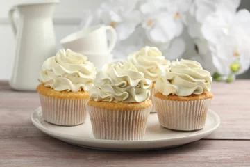 Foto op Canvas Tasty cupcakes with vanilla cream on pink wooden table, closeup © New Africa