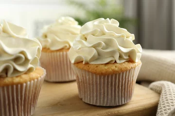 Tuinposter Tasty cupcakes with vanilla cream on wooden board, closeup © New Africa