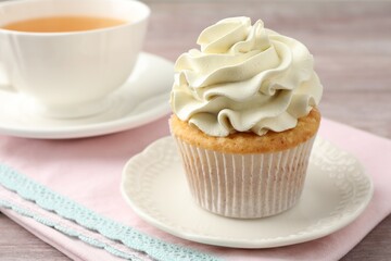 Tasty cupcake with vanilla cream on pink wooden table, closeup