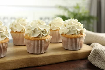 Zelfklevend Fotobehang Tasty cupcakes with vanilla cream on wooden table, closeup © New Africa