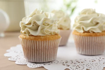 Fotobehang Tasty cupcakes with vanilla cream on light wooden table, closeup © New Africa