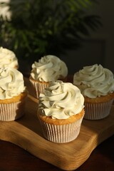 Tasty cupcakes with vanilla cream on wooden table, closeup