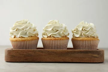 Keuken spatwand met foto Tasty cupcakes with vanilla cream on light grey table, closeup © New Africa