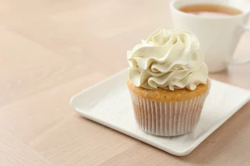 Foto op Aluminium Tasty cupcake with vanilla cream on light wooden table, closeup. Space for text © New Africa