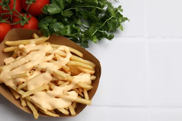 Rolgordijnen Delicious French fries with cheese sauce, tomatoes and parsley on white tiled table, closeup. Space for text © New Africa