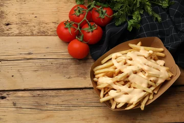 Rolgordijnen Delicious French fries with cheese sauce, tomatoes and herbs on wooden table, flat lay. Space for text © New Africa