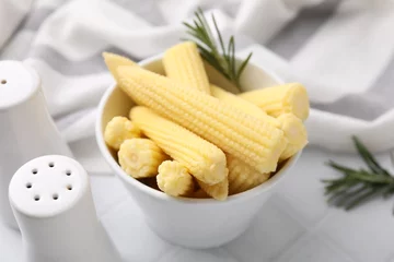 Rolgordijnen Tasty fresh yellow baby corns in bowl on white tiled table, closeup © New Africa
