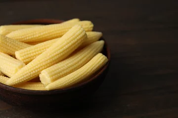 Rolgordijnen Tasty fresh yellow baby corns in bowl on wooden table, closeup. Space for text © New Africa