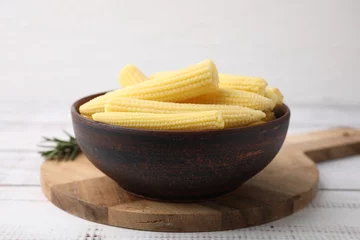 Gordijnen Tasty fresh yellow baby corns in bowl on white wooden table © New Africa