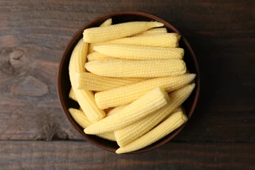 Gordijnen Tasty fresh yellow baby corns in bowl on wooden table, top view © New Africa