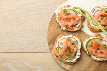 Tasty canapes with salmon served on wooden table, top view. Space for text