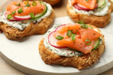  Tasty canapes with salmon, cucumber, radish and cream cheese on table, closeup © New Africa