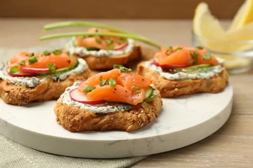 Fotobehang Tasty canapes with salmon, cucumber, radish and cream cheese on wooden table, closeup © New Africa