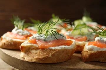 Gordijnen Tasty canapes with salmon, cucumber, cream cheese and dill on wooden stand, closeup © New Africa