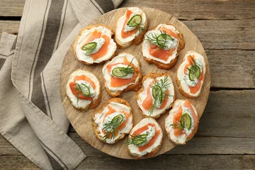 Fotobehang Tasty canapes with salmon, cucumber, cream cheese and dill on wooden stand, top view © New Africa