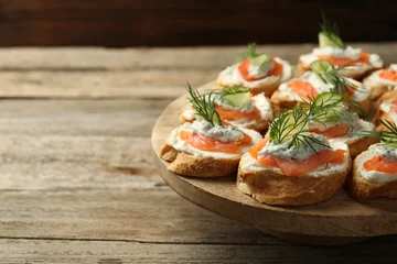 Fotobehang Tasty canapes with salmon, cucumber, cream cheese and dill on wooden stand, closeup. Space for text © New Africa