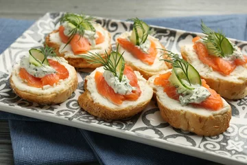  Tasty canapes with salmon, cucumber, cream cheese and dill on table, closeup © New Africa