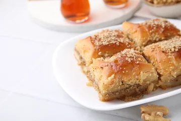 Fotobehang Eastern sweets. Pieces of tasty baklava and tea on white tiled table, closeup. Space for text © New Africa