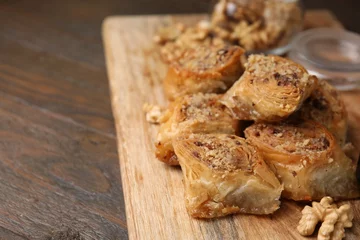 Rolgordijnen Eastern sweets. Pieces of tasty baklava on wooden table, closeup. Space for text © New Africa