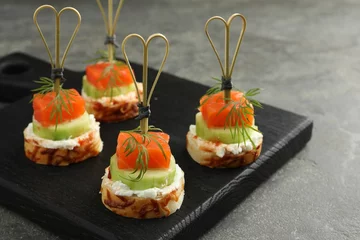 Foto op Canvas Tasty canapes with salmon, cucumber, bread and cream cheese on grey table, closeup © New Africa