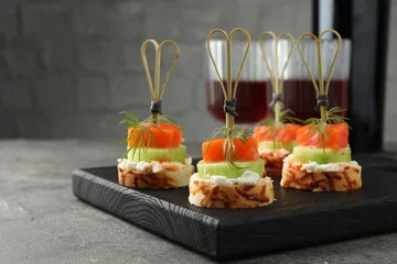 Poster Tasty canapes with salmon, cucumber, bread and cream cheese served on grey table, closeup © New Africa