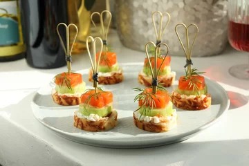 Poster Tasty canapes with salmon, cucumber, bread and cream cheese on white table © New Africa